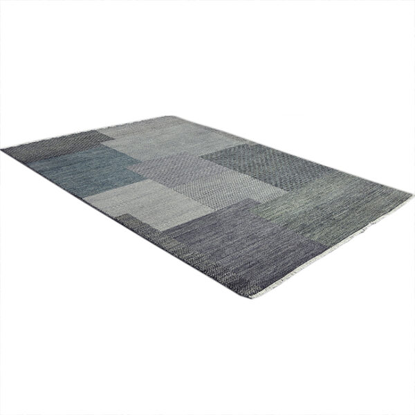 Diagonaal aanzicht van vloerkleed BRETTI, in de kleur blauw zwart gemaakt van wol.