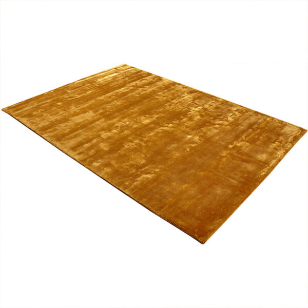 Diagonaal aanzicht van vloerkleed FLAVIA, in de kleur oker gemaakt van viscose.