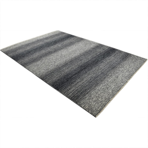 Diagonaal aanzicht van vloerkleed LUCERA, in de kleur zwart grijs gemaakt van wol.