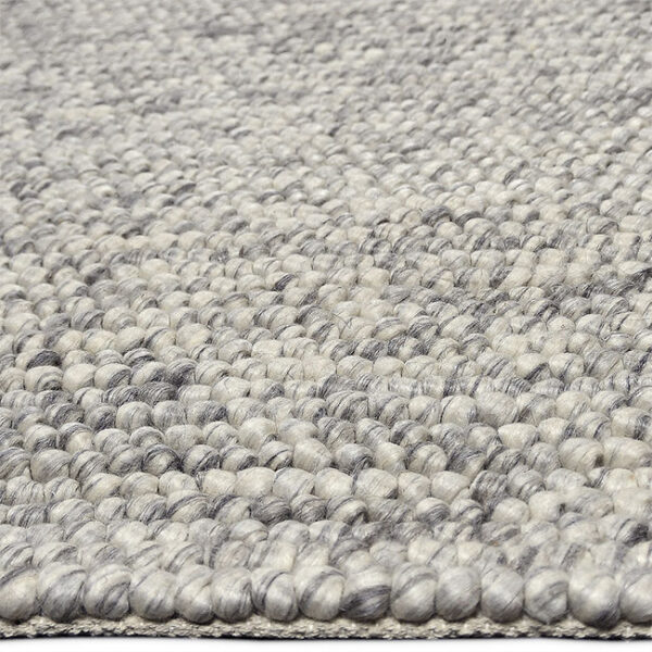 Zijkant detail aanzicht van vloerkleed NURA, in de kleur grijs wit gemaakt van wol.