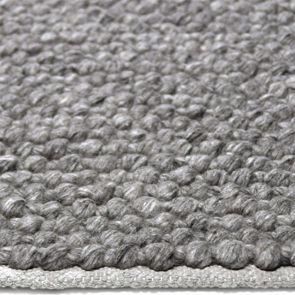 Zijkant detail aanzicht van vloerkleed RENO, in de kleur grijs gemaakt van wol.