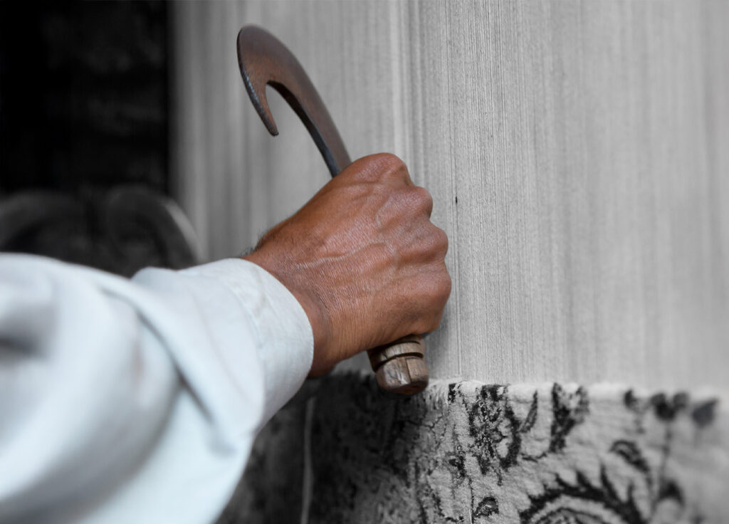 Ambachtelijke hand die werkt aan een handgemaakt vloerkleed in het atelier van Perez Vloerkleden